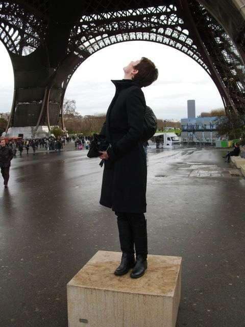 Eine Person steht auf einem Podest und schaut nach oben unter dem Eiffelturm in Paris.