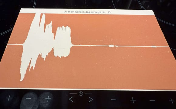 Illustration of a sound wave displayed on an orange background with German text at the top.