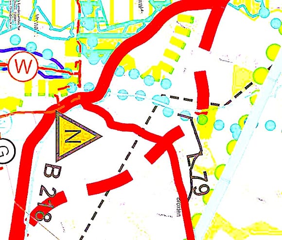 Ein farbenfroher Stadtplan mit Straßen und einem großen roten Weg, der durch die Karte verläuft. Markierungen und Symbole zeigen verschiedene Orte und Richtungen an, einschließlich eines Nordsymbols.