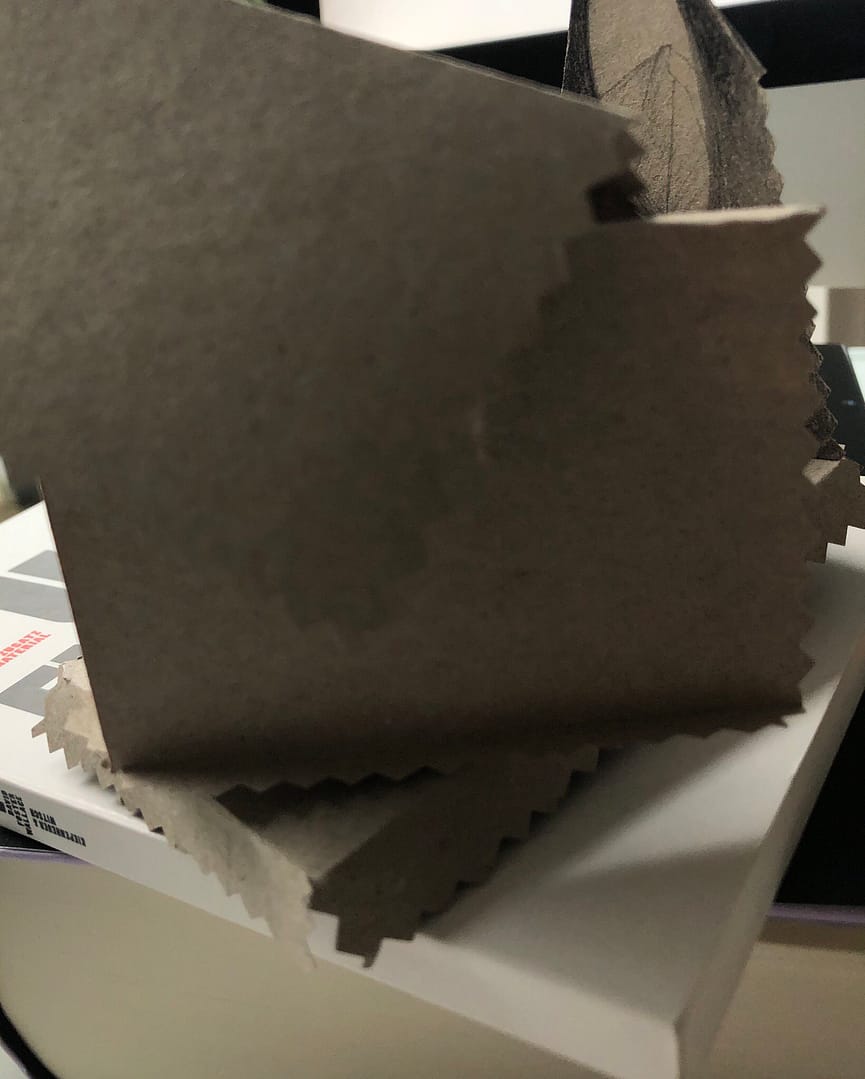 Ein Stapel aus braunem Papier mit gezackten Kanten, auf einem weißen Untergrund.